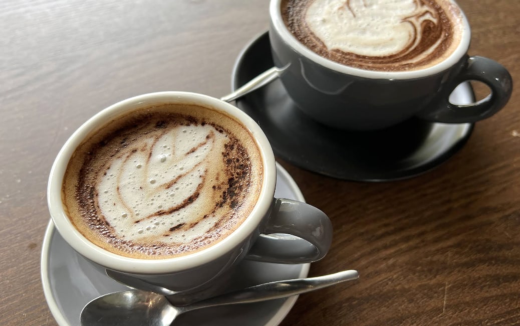 Provided screenshot of two coffees on a wooden table.